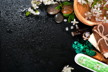 Spa concept on a dark background. Sea salt, flowering branches of cherry, aromatic oils