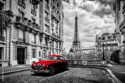 Artistic Paris, France. Eiffel Tower seen from the street with red retro limousine car.
