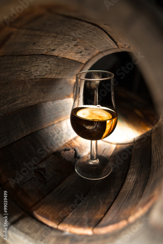 A glass of whiskey on a background of oak barrels