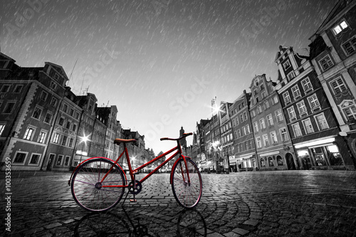 Vintage red bike on cobblestone historic old town in rain. Wroclaw, Poland.