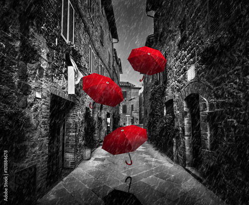  Umrbellas flying with wind and rain on dark street in an old Italian town in Tuscany, Italy