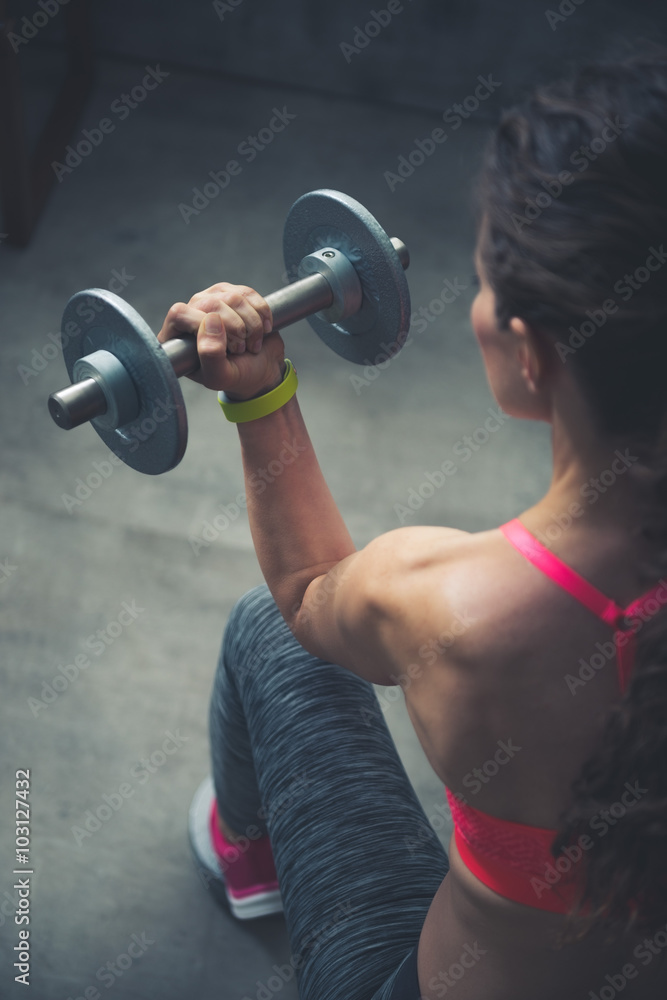 Seen from behind fitness woman lifting dumbbell