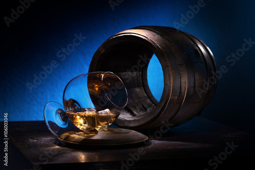 A glass of brandy and ice on a background of empty oak barrels