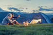Three friends camping with fire on mountain at sunset Three friends camping with fire on mountain at sunset