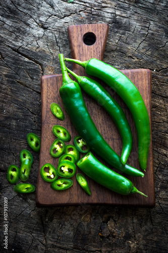 Fresh green chilli on old wooden background