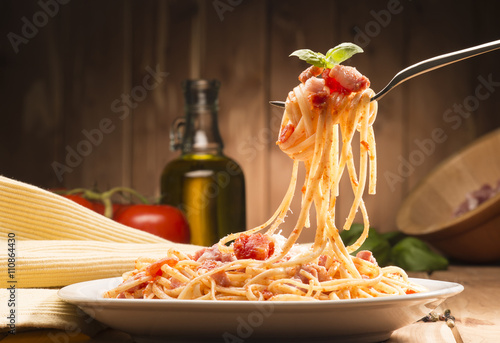 Fotoobraz na płótnie spaghetti z sosem amatriciana w naczyniu na drewnianym stole