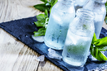 Very cold mineral water with ice in a misted glass bottles, dark