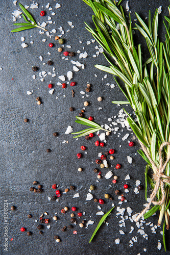 Top view salt and pepper on dark stone with rosemary