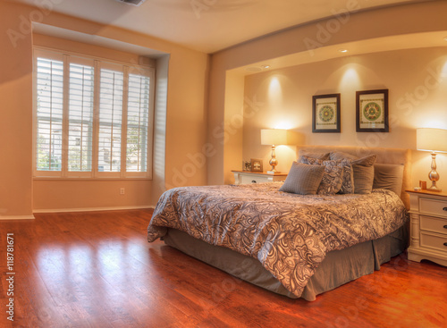 Plakat Irvine, CA, usa - Sierpień 19, 2016: Wielka mistrzowska sypialnia z recessed oświetlenie, drewniane podłoga i feng shui wystrój. Łóżko ma kołdrę kołdrą w kolorze brązowym z puszystymi poduszkami.