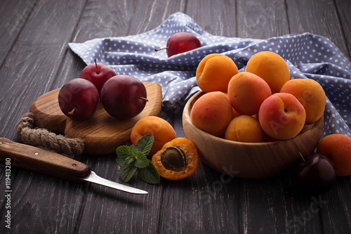 Sweet apricots and plums on wooden background