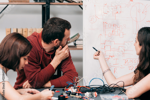 Plakat Schemat połączeń omawiających w laboratorium. Młodzi inżynierowie tworzący nowy model konstrukcji elektronicznej, eksperymentalne badania sposobów łączenia kabli na schemacie