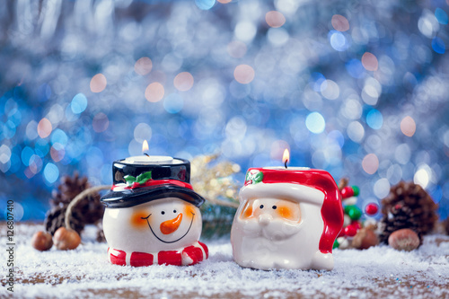 Santa Claus And Snowman Candle Holders On Snowy Wood