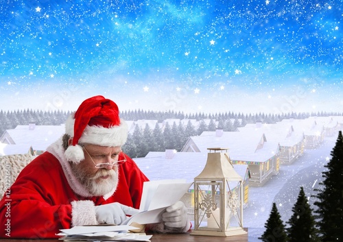 Santa sitting at table and reading christmas letter