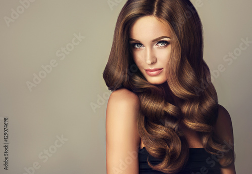 Plakat Piękna modelka z długimi falującymi i lśniącymi włosami. Brunetka kobieta z kręcone fryzury