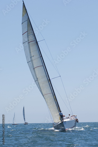 Overview of sailboats racing in the blue and calm ocean against sky