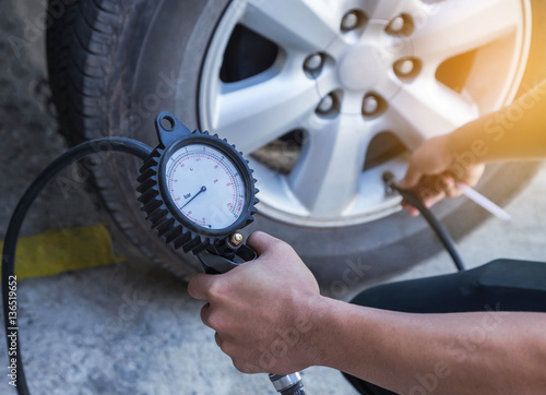 Zdjęcie XXL Zamyka w górę mechanika pompowania opony i sprawdzać ciśnienia powietrza z wymiernika naciskiem