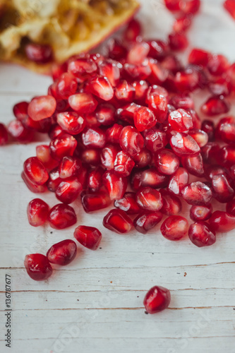 Pomegranate peel and seeds over white wooden background.