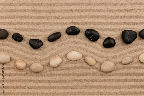 Fototapeta Two rows of stones lying on the sand, with space for text.