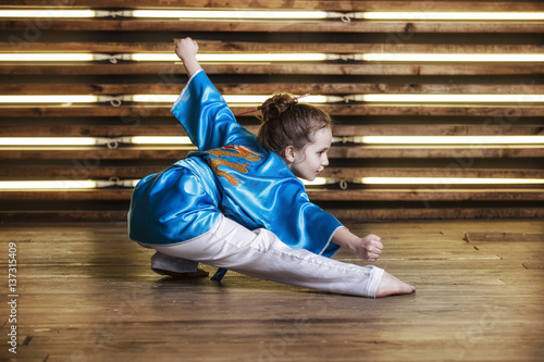 Plakat Całkiem mała dziewczynka w pokoju w sportowej odzieży dla sztuk walki to Wushu