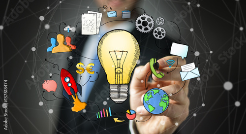 Businessman drawing a lightbulb with a pen with multimedia icons