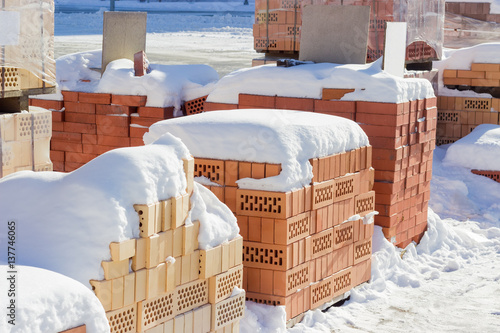Perforated red bricks covered snow on an outdoor warehouse
