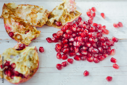 Pomegranate peel and seeds over white wooden background.