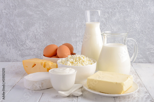 Plakat Świeże produkty mleczne. Mleko, ser, brie, Camembert, masło, jogurt, twaróg i jajka na drewnianym stole.
