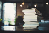 piles of books on table over blurred library background.