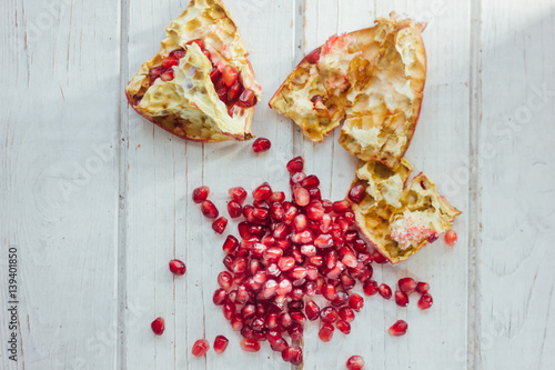 Pomegranate peel and seeds over white wooden background.
