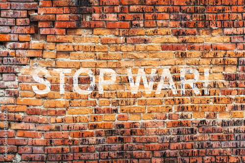 Text STOP WAR on stained old orange brick wall texture background