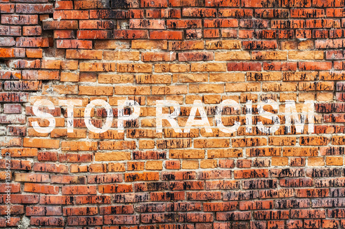 Text STOP RACISM on stained old orange brick wall texture background