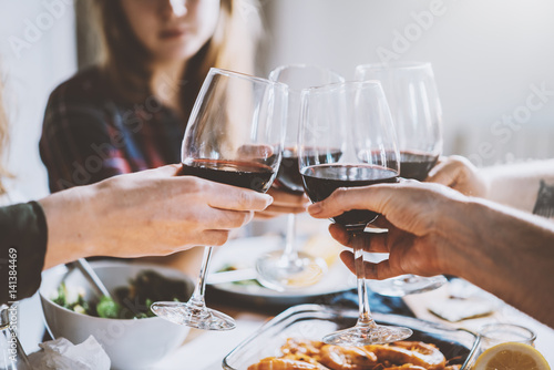 Plakat Szczęśliwi przyjaciele robi okrzyki z szkłami czerwone wino, grupa ludzi świętuje rocznicę w domu, przytulna atmosfera, rodzinny obiad w restauracji, wspólnoty i tradycyjny pomysł
