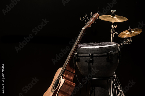 Fototapeta na wymiar percussion instruments with an acoustic guitar on wooden boards with a black background