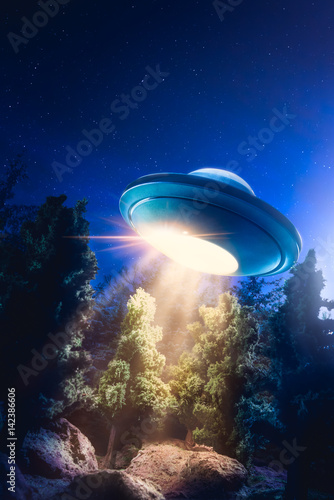 Fotoobraz na płótnie Wysoki kontrast obrazu UFO lecący nad lasem z wiązki światła w nocy