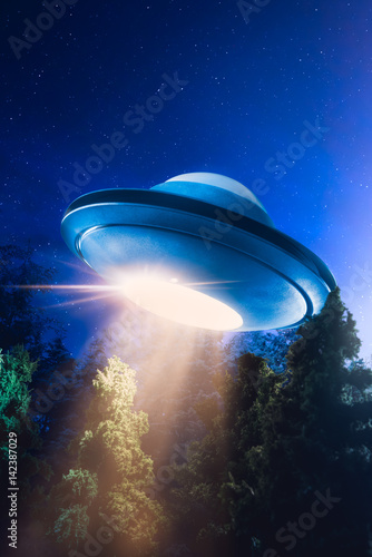 Fotoobraz na płótnie Wysoki kontrast obrazu UFO lecący nad lasem z wiązki światła w nocy