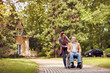 daughter and senior man in wheelchair on walking green nature. daughter and senior man in wheelchair on walking green nature.