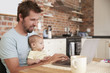 Father Working From Home On Laptop With Baby Son Father Working From Home On Laptop With Baby Son