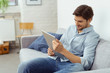 mann sitzt auf dem sofa und schaut auf sein tablet mann sitzt auf dem sofa und schaut auf sein tablet