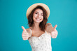 Happy young girl in beach hat showing thumbs up gesture Happy young girl in beach hat showing thumbs up gesture