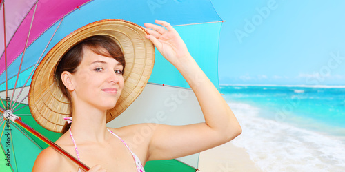 Plakat Młoda atrakcyjna kobieta w słomianego kapeluszu use słońca ochronnym parasolem na plaży. Powitanie z wakacji. Ludzie i zajęcia rekreacyjne.