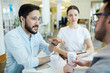 Group of business people sitting discussing work in office: portrait of Asian man gesturing actively talking to colleagues Group of business people sitting discussing work in office: portrait of Asian man gesturing actively talking to colleagues