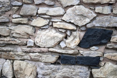 Alte Natursteinmauer mit zwei schwarzen Steinen, Textur, Hintergrund, Textfreiraum