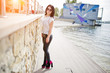 Portrait of brunette girl on women's leather pants and white blouse, sunglasses, against iron railings with wall. Portrait of brunette girl on women's leather pants and white blouse, sunglasses, against iron railings with wall.