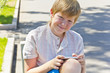 Blond boy with mobile phone sitting on a bench Blond boy with mobile phone sitting on a bench