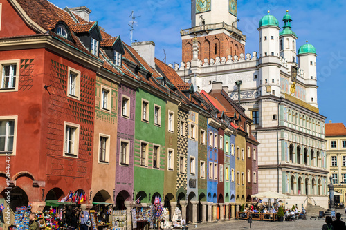 Plakat Niezidentyfikowani ludzie przechodzą obok kolorowych domów Rzemieślników i Ratusza na Starym Rynku, Poznań