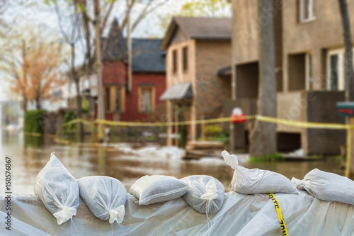 Plakat Zamknij shot of Sandbags ochrony przeciwpowodziowej z zalanych domów w tle