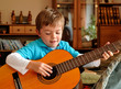 Ein Junge sitzt auf der Couch und spielt auf einer Gitarre Ein Junge sitzt auf der Couch und spielt auf einer Gitarre