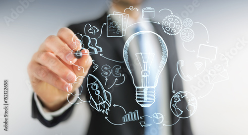 Businessman drawing a lightbulb with a pen with multimedia icons