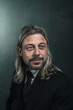 Smiling retro victorian style man with blond long hair and beard. Wearing black suit and tie. Smiling retro victorian style man with blond long hair and beard. Wearing black suit and tie.