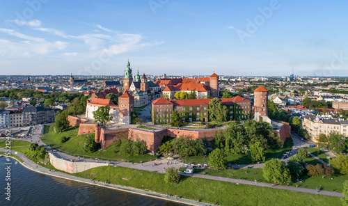 Plakat Kraków, Polska. Wzgórze Wawelskie z zabytkowym zamkiem królewskim i katedrą, rzeką Wisłą, parkiem i spacerowiczami. Widok z lotu ptaka o zachodzie słońca.